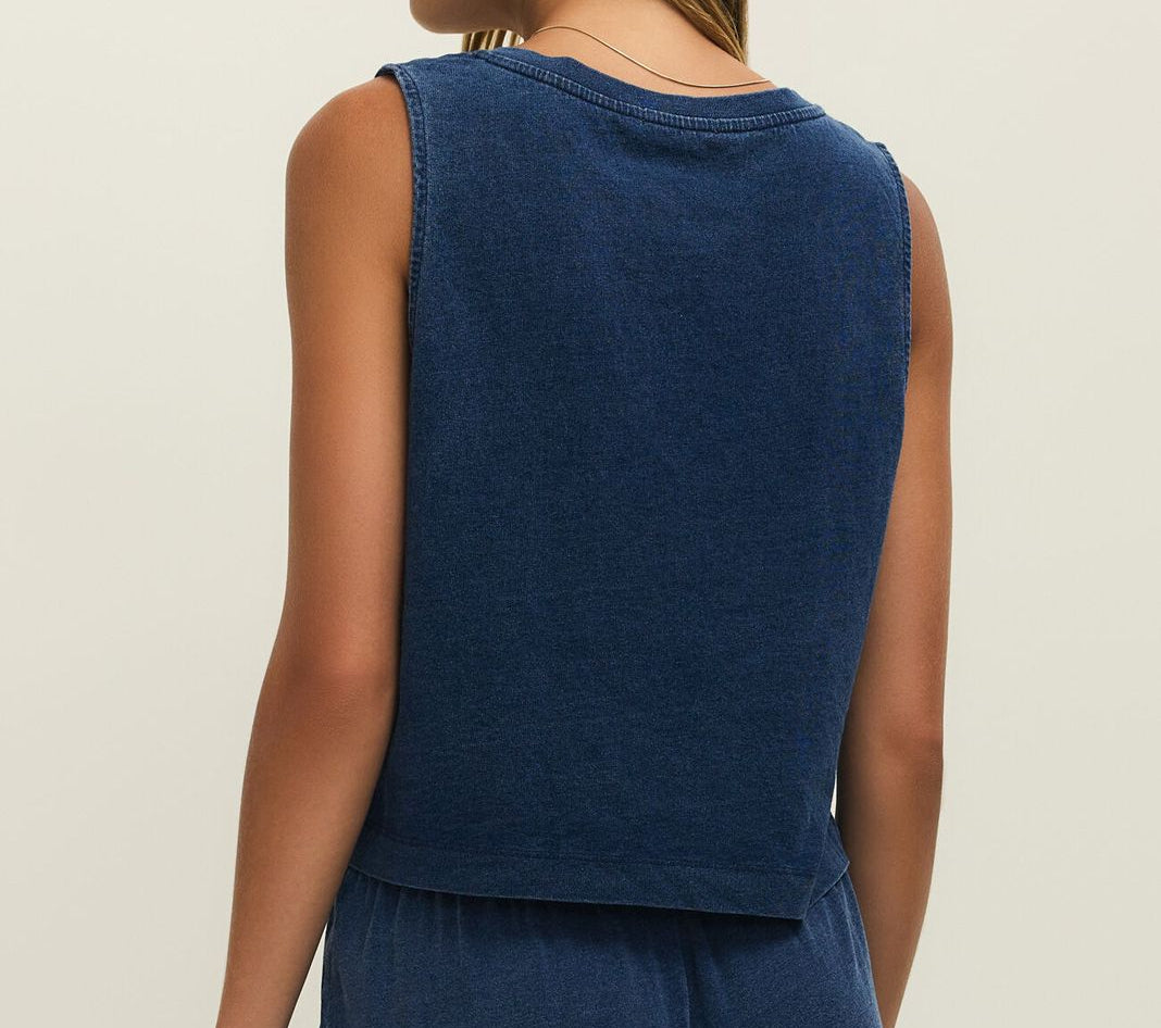 Woman wearing a blue sleeveless top and pants on a beige background