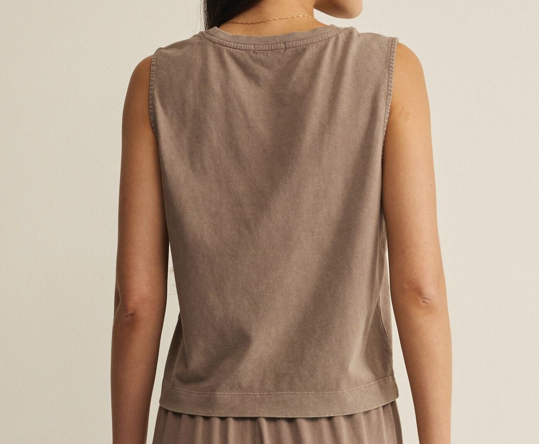 Woman wearing a brown sleeveless top and pants against a beige background