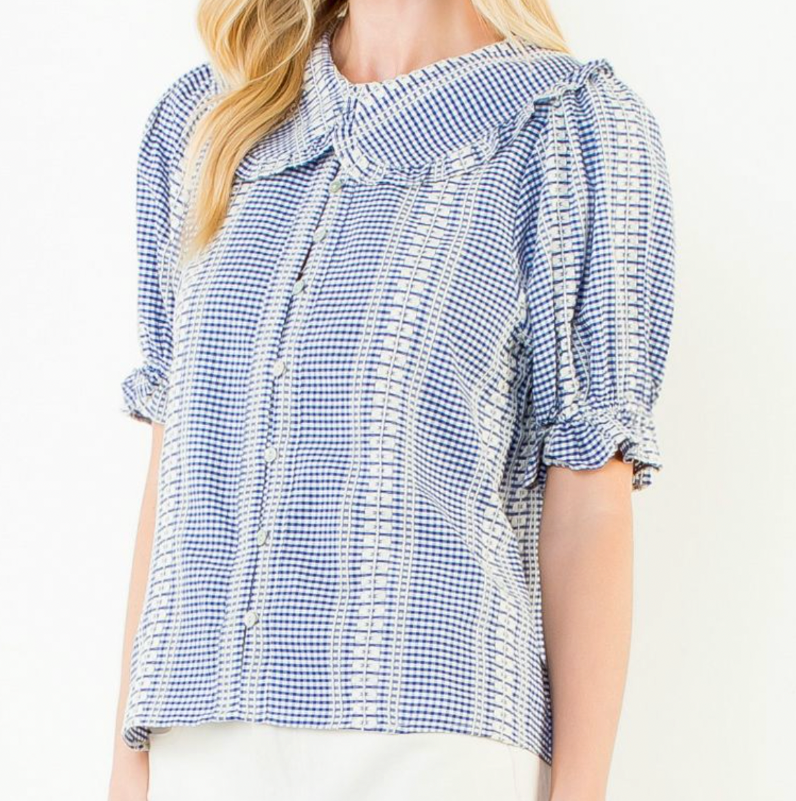 Close up of woman wearing a blue and white checkered blouse with ruffled sleeves on a white background