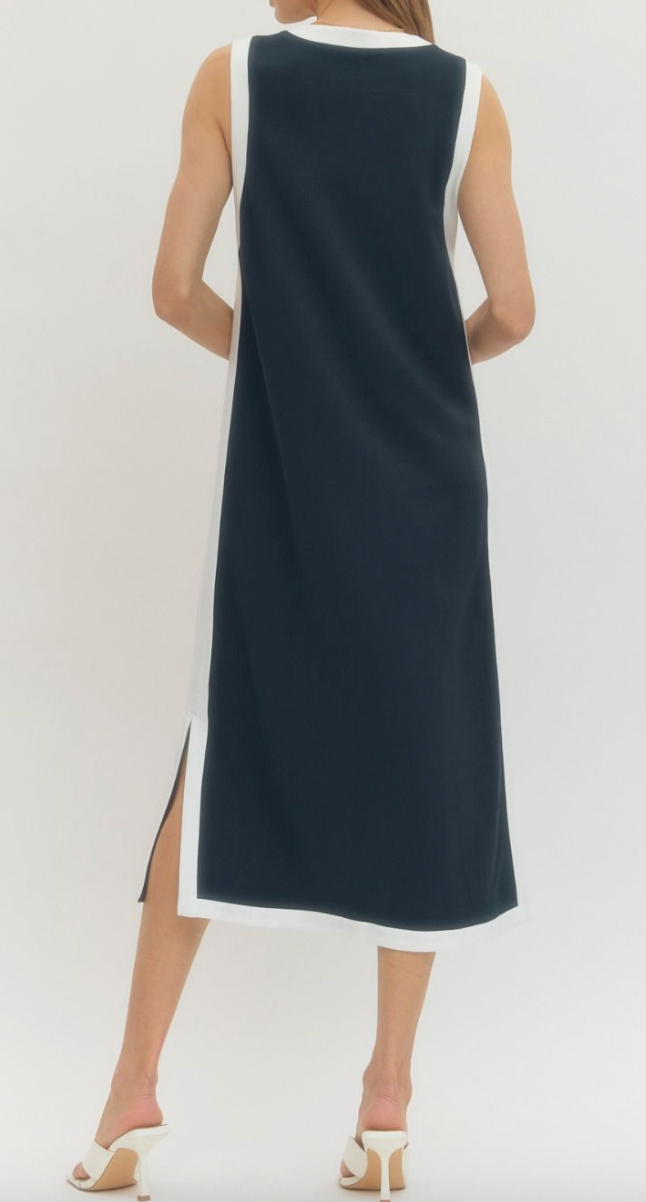 Woman wearing a sleeveless navy dress with a white top on a white background