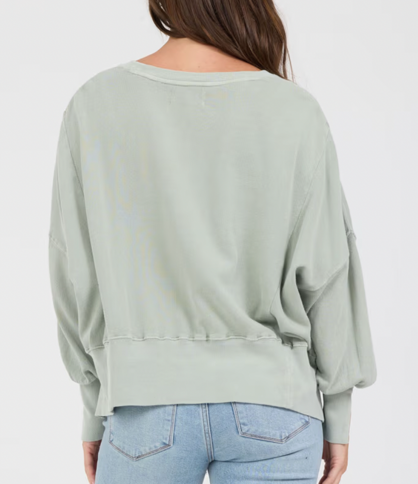Light green long-sleeve top worn by a person on a white background