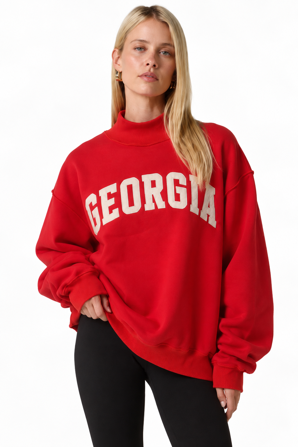 A blonde woman wearing a red mock-neck sweatshirt with 'GEORGIA' printed in white arched block letters across the chest, paired with black pants, against a plain white background.