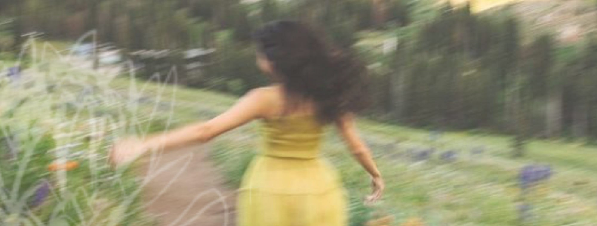 Woman in a yellow dress running through a field with a close-up of a flower drawing at the bottom.
