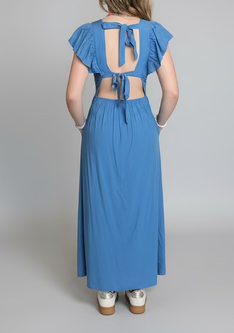 Woman wearing a blue dress with cut-out back on a gray background