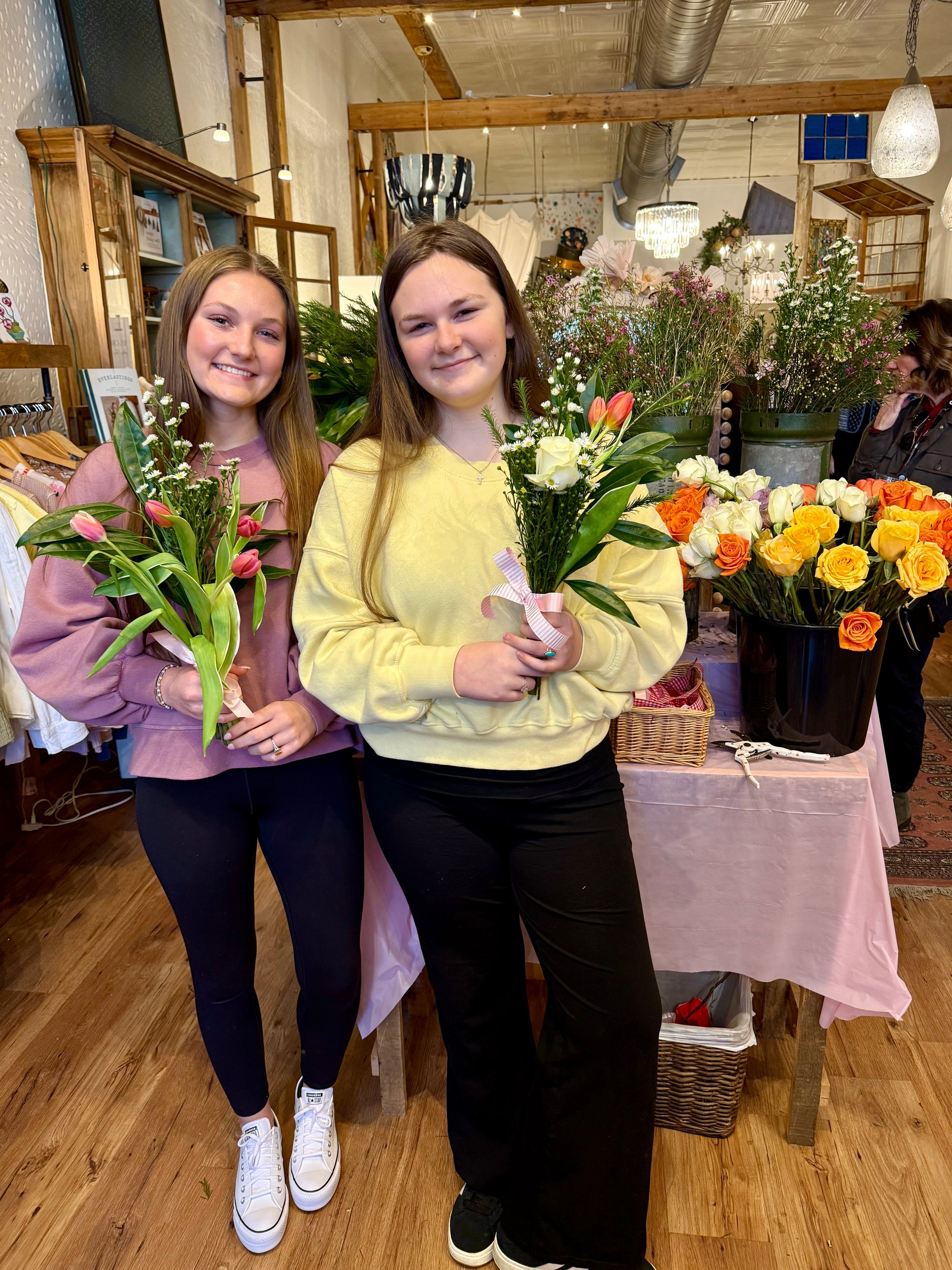 Two women holding flower bouquets in a floral shop.