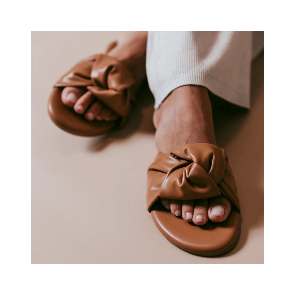 Brown leather sandals worn on a neutral background
