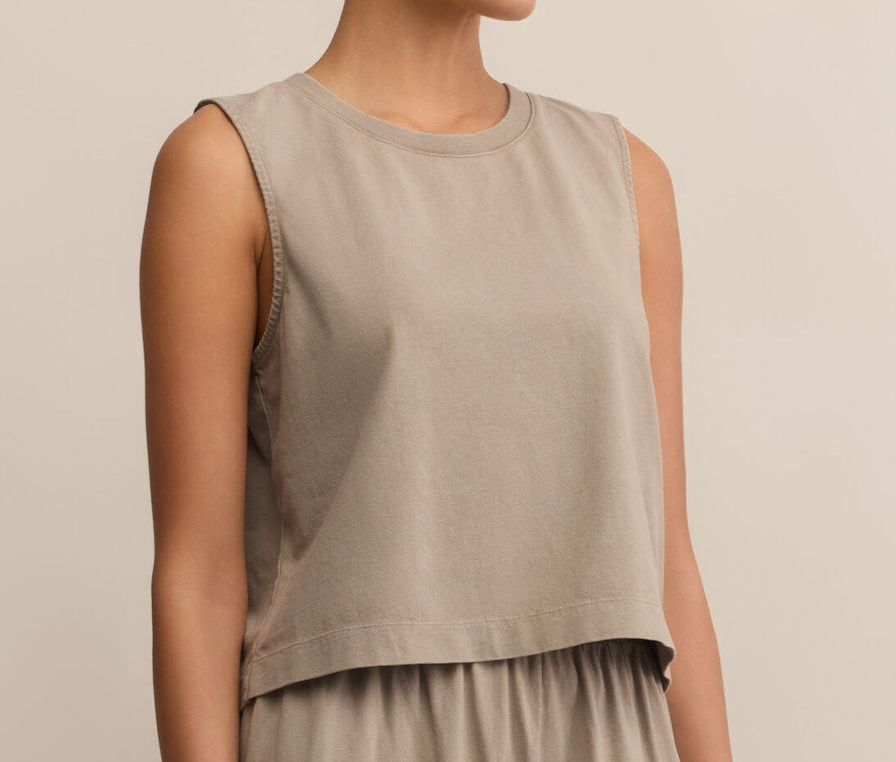 Person wearing a beige sleeveless top and pants on a beige background