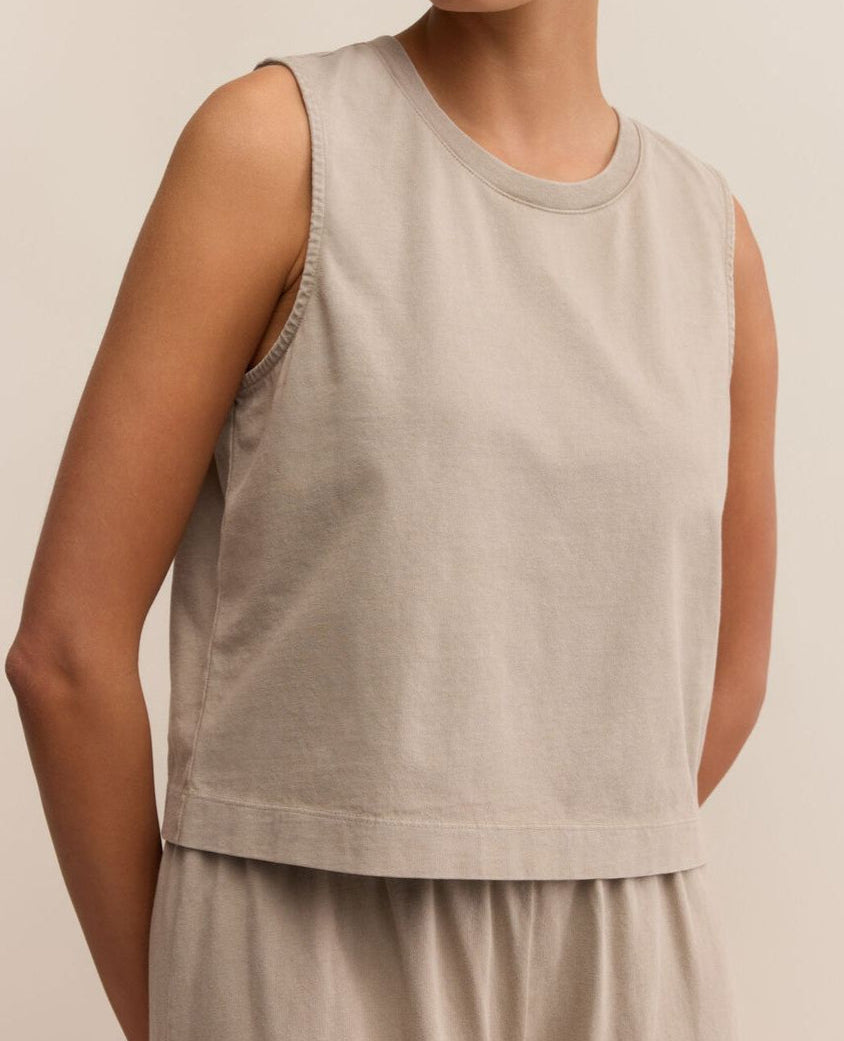 Person wearing a beige sleeveless top and pants against a neutral background