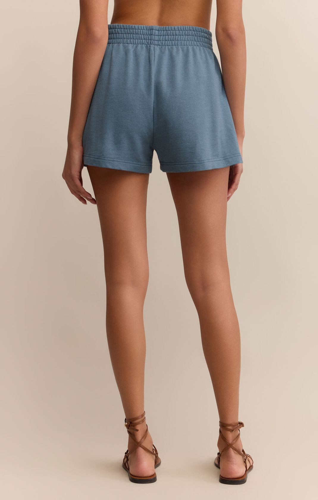 Blue shorts worn by a person on a beige background