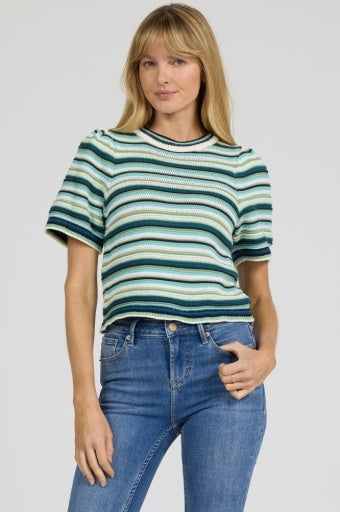 Woman wearing a striped sweater and blue jeans on a plain background