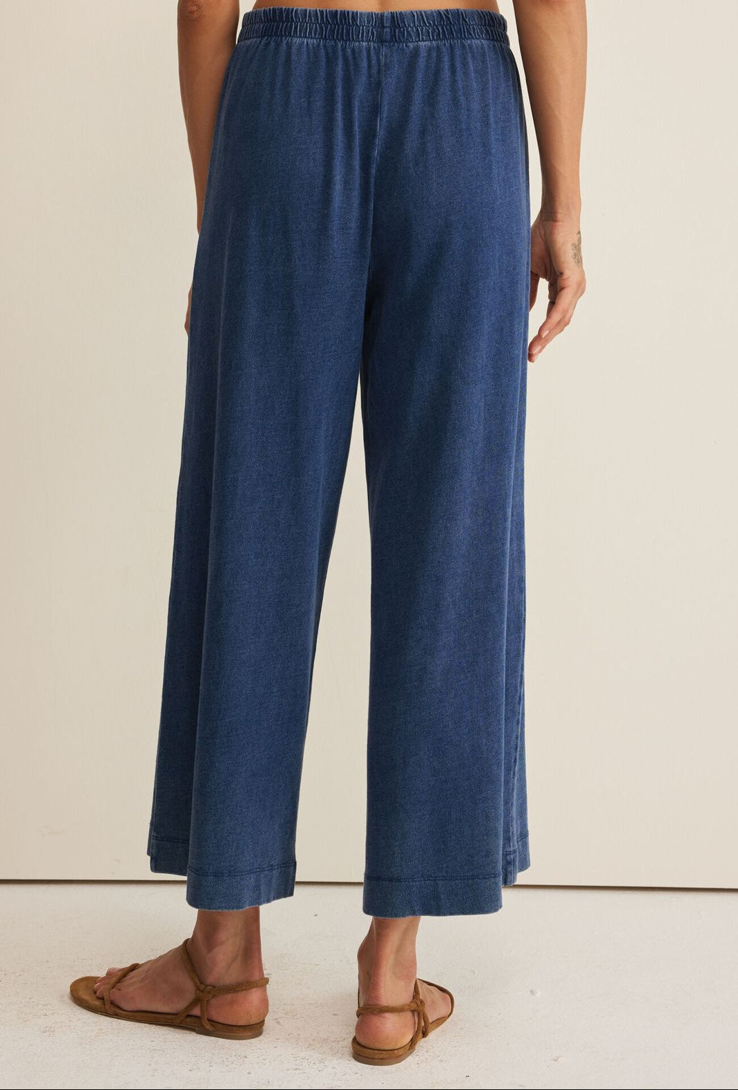 Blue denim pants worn by a person on a beige background