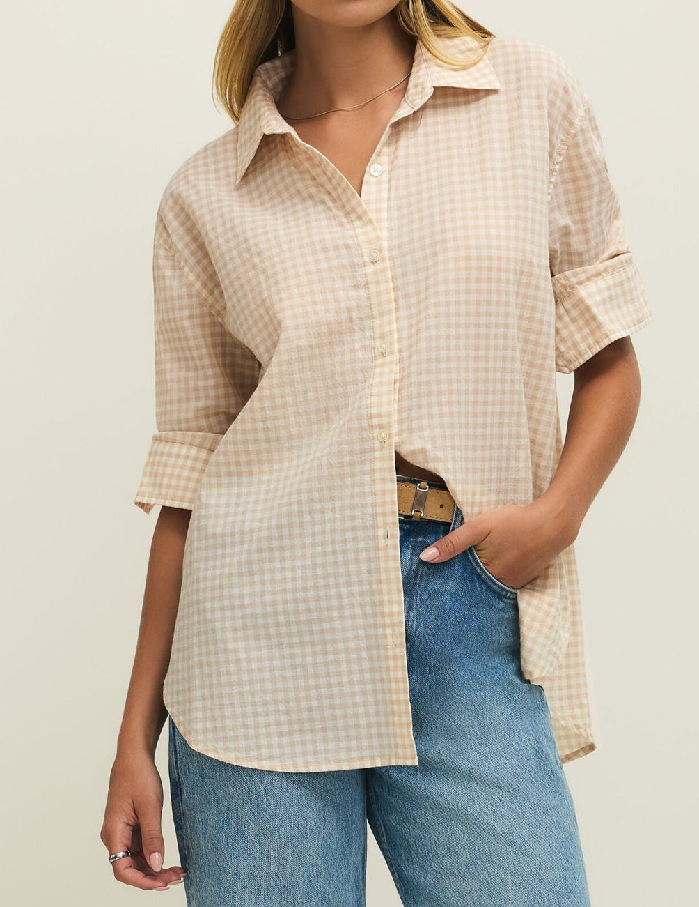 Woman wearing a checkered shirt and jeans on a plain background