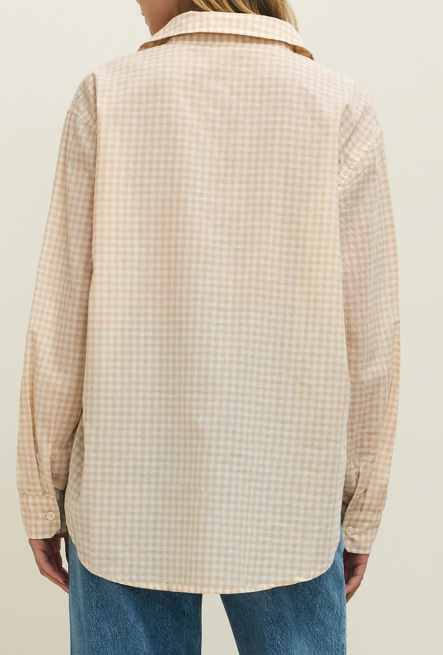 Person wearing a beige checkered shirt and blue jeans on a plain background