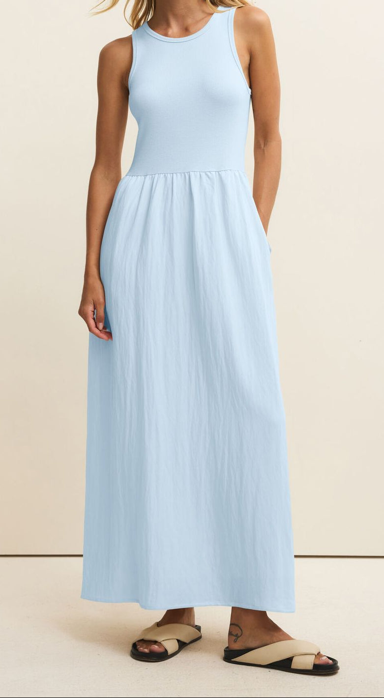 Woman wearing a light blue sleeveless dress against a beige background