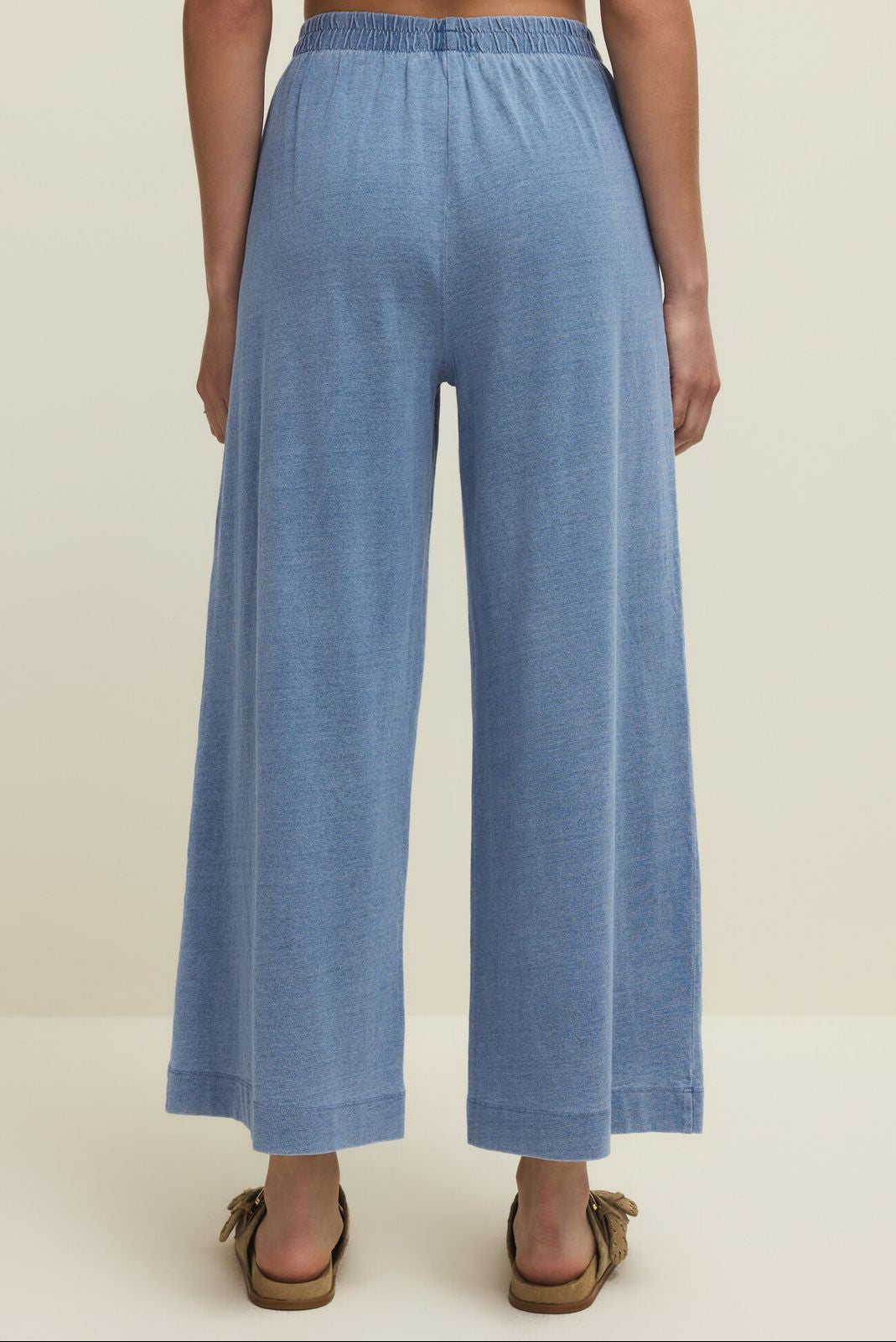 Blue wide-leg pants worn by a person on a beige background