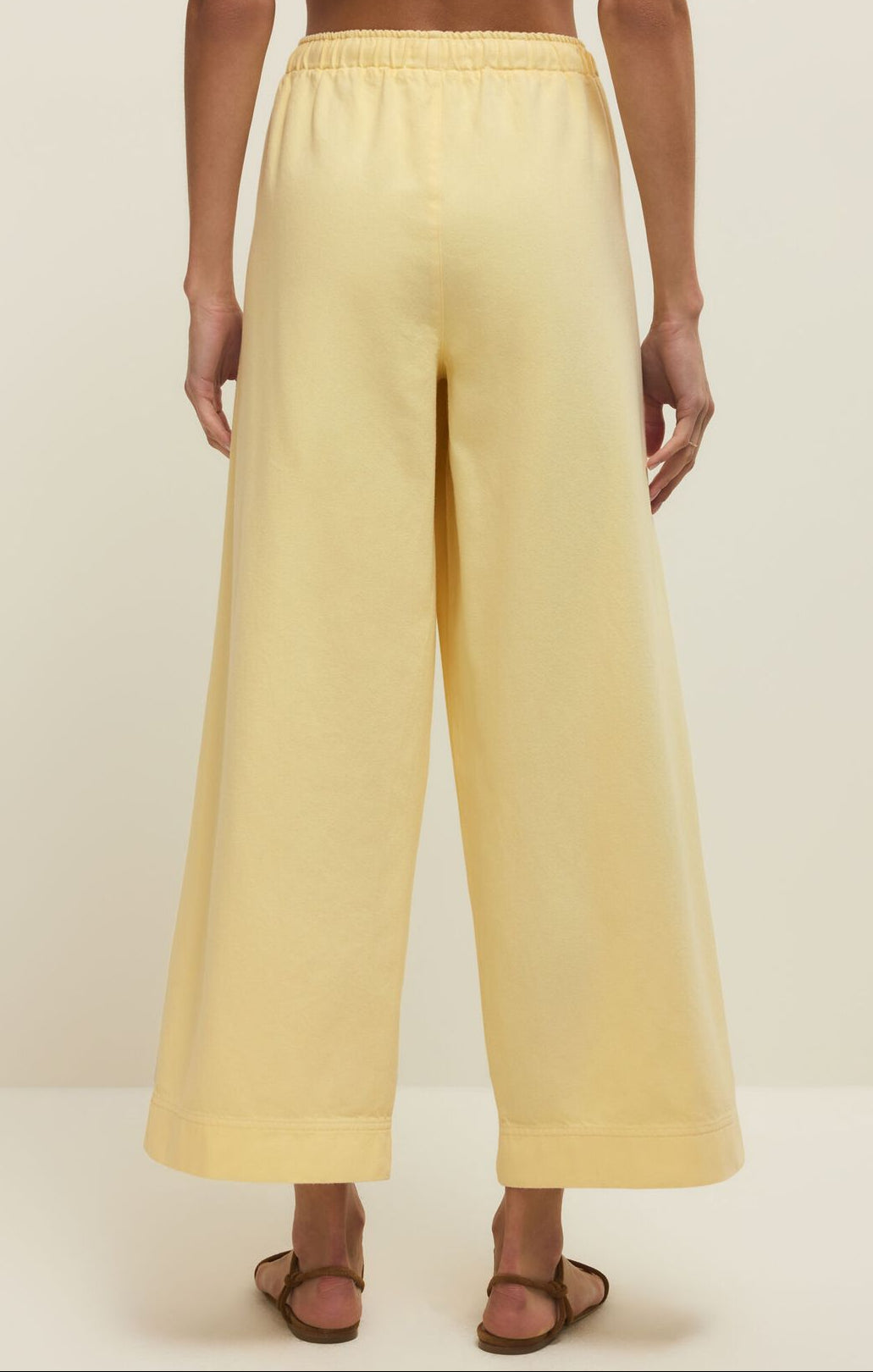 Person wearing light yellow wide-leg pants on a plain background