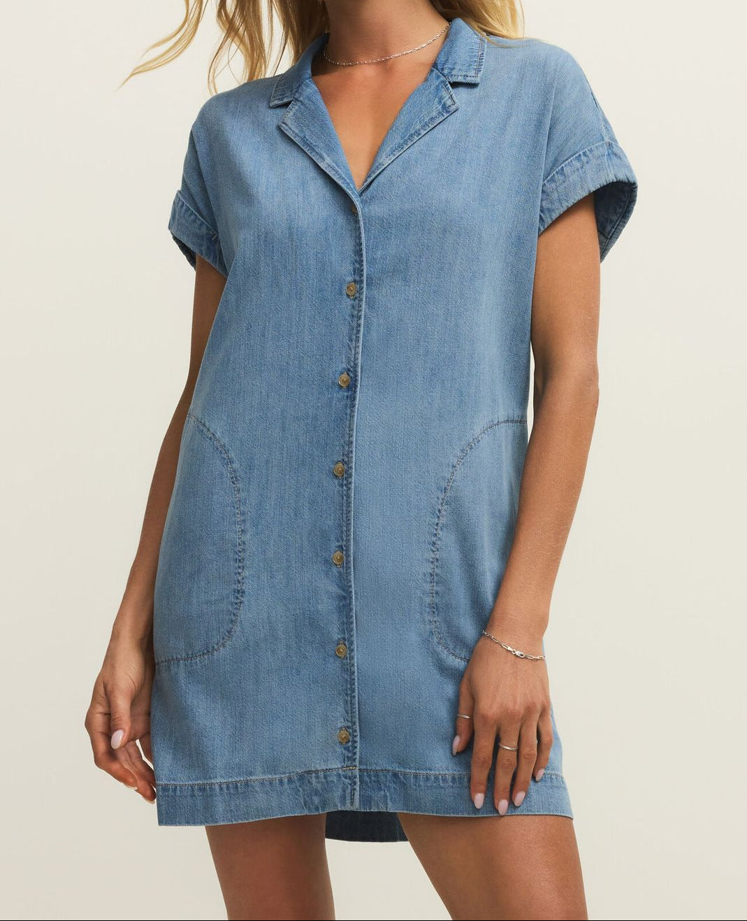 Woman wearing a denim dress against a plain background