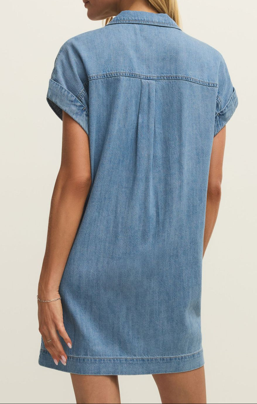 Woman wearing a blue denim dress against a neutral background