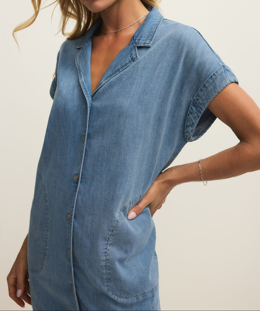 Woman wearing a blue denim dress against a plain background