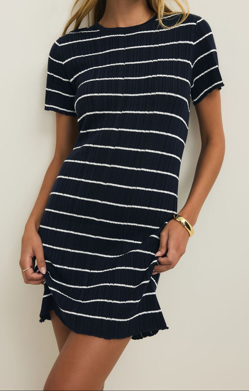 Woman wearing a navy and white striped dress against a plain background