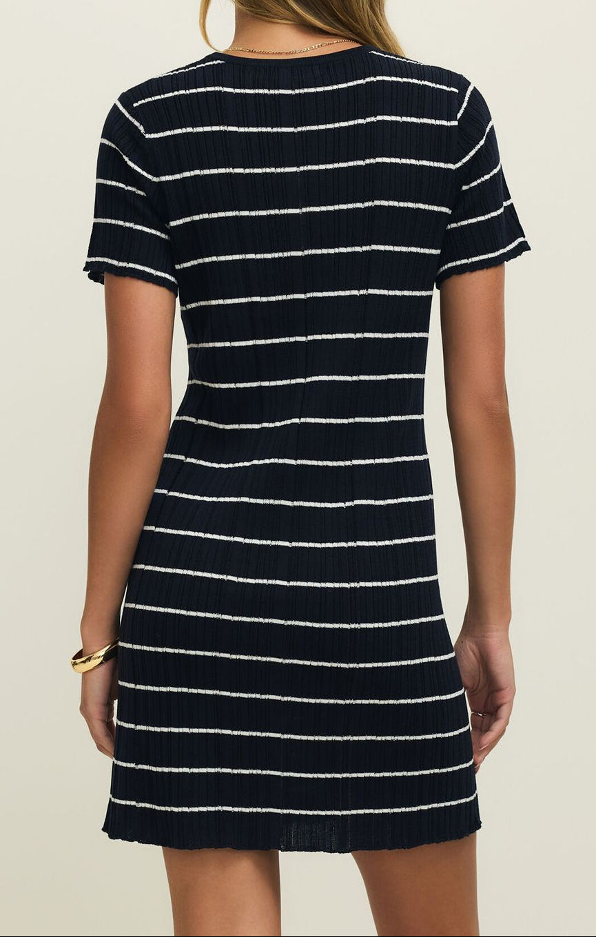 Woman wearing a black and white striped dress against a plain background