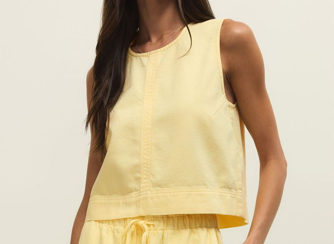 Woman wearing a yellow sleeveless top and wide-leg pants against a plain background