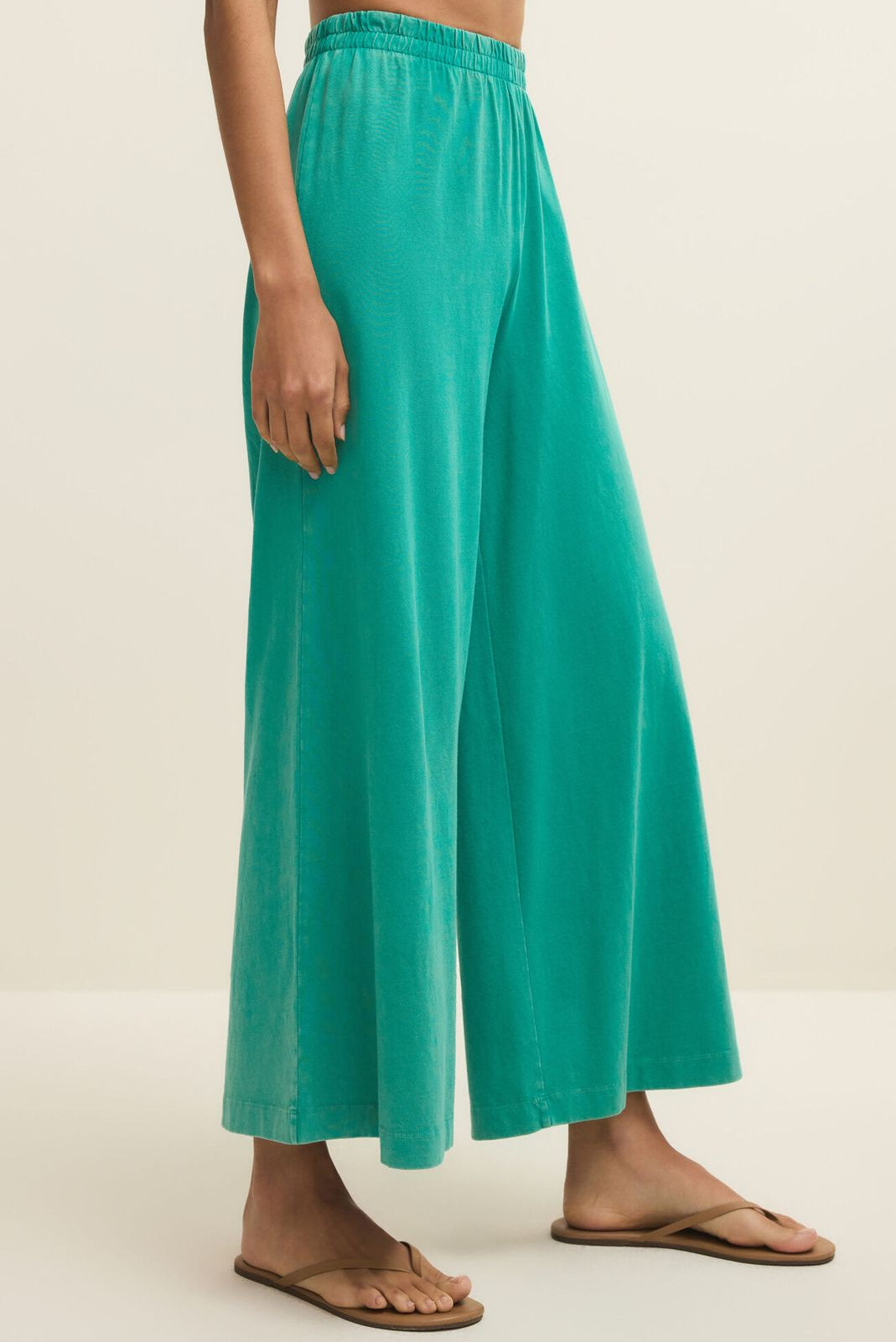 Teal wide-leg pants worn by a person on a beige background