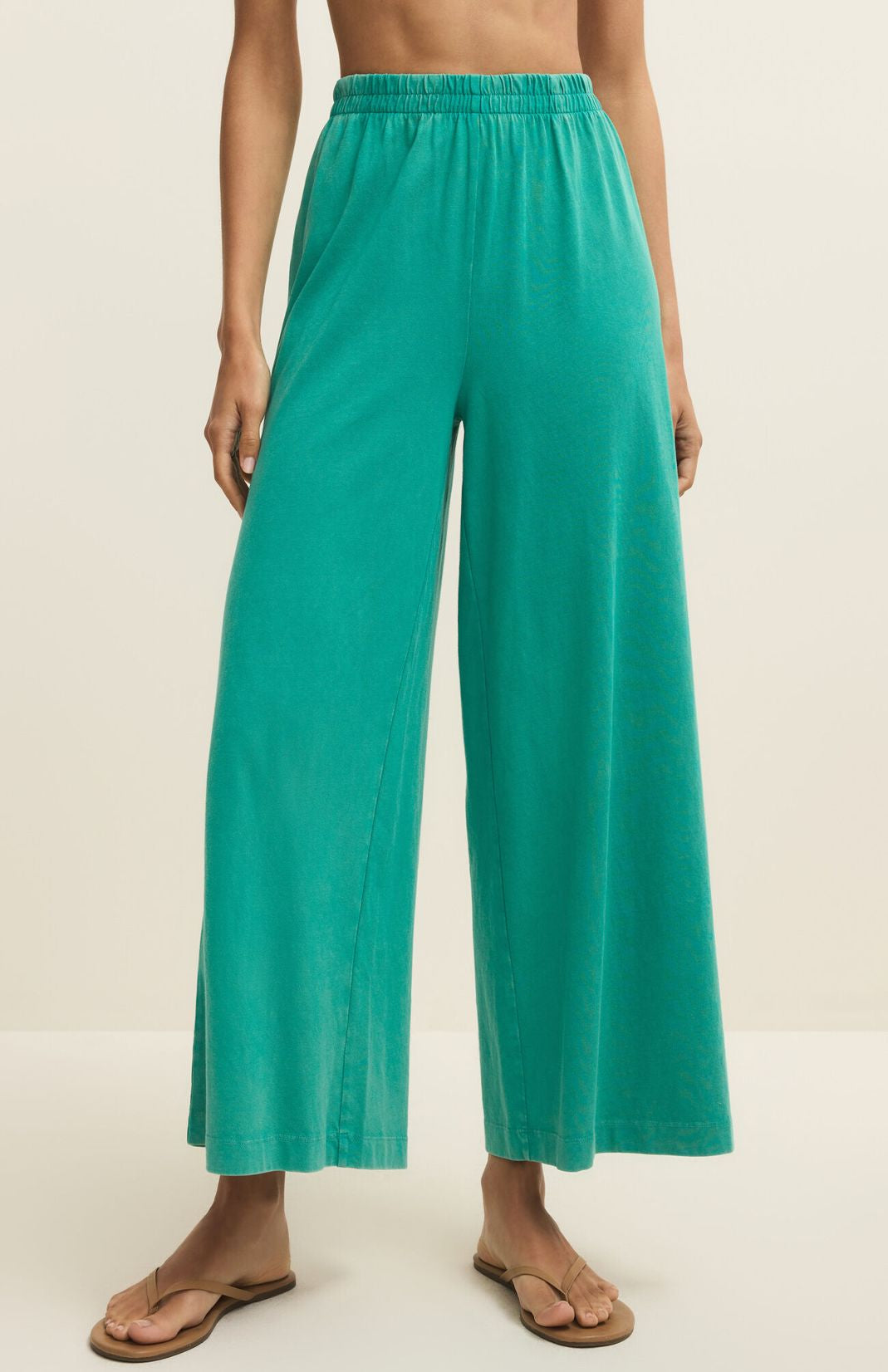 Teal wide-leg pants worn by a person on a beige background