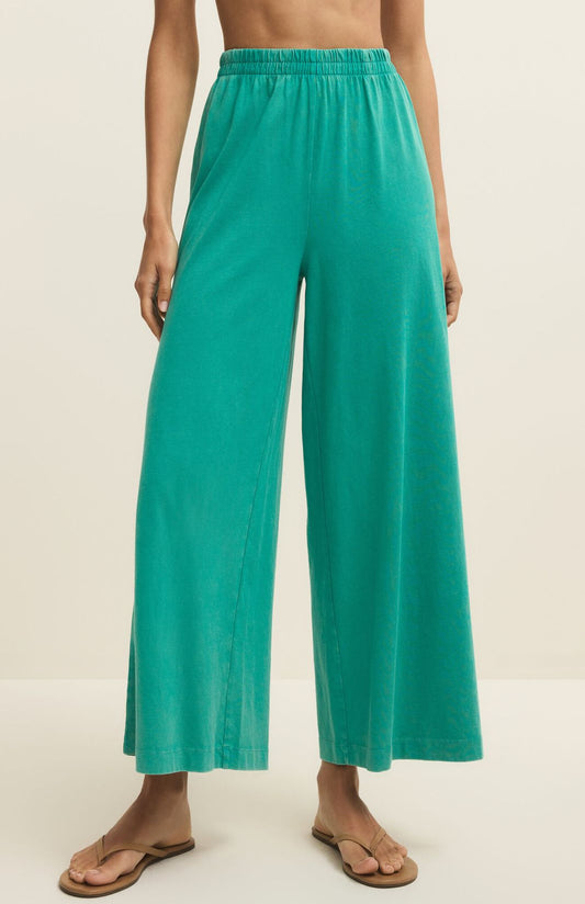 Teal wide-leg pants worn by a person on a beige background