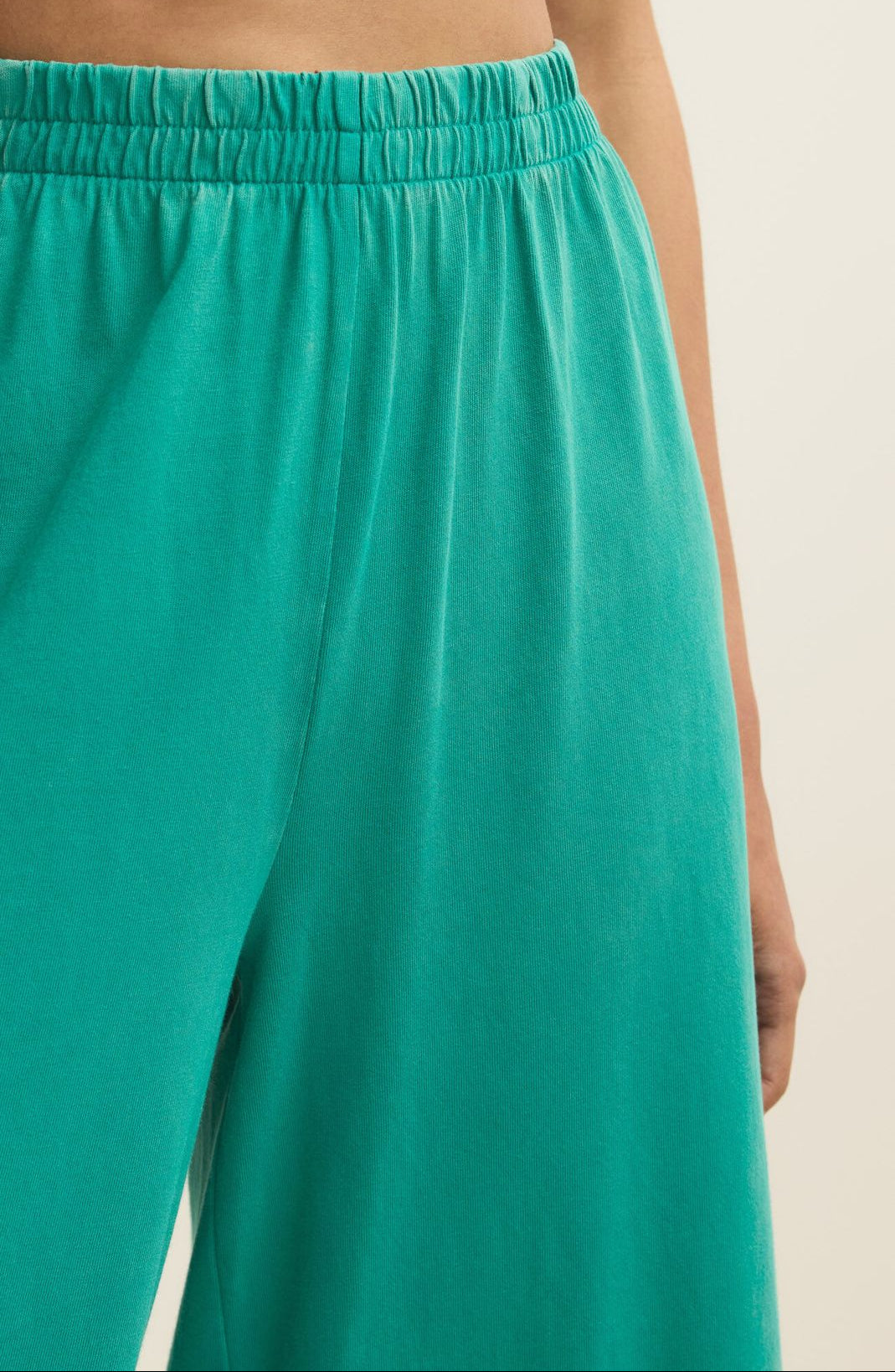 Teal pants with an elastic waistband on a beige background