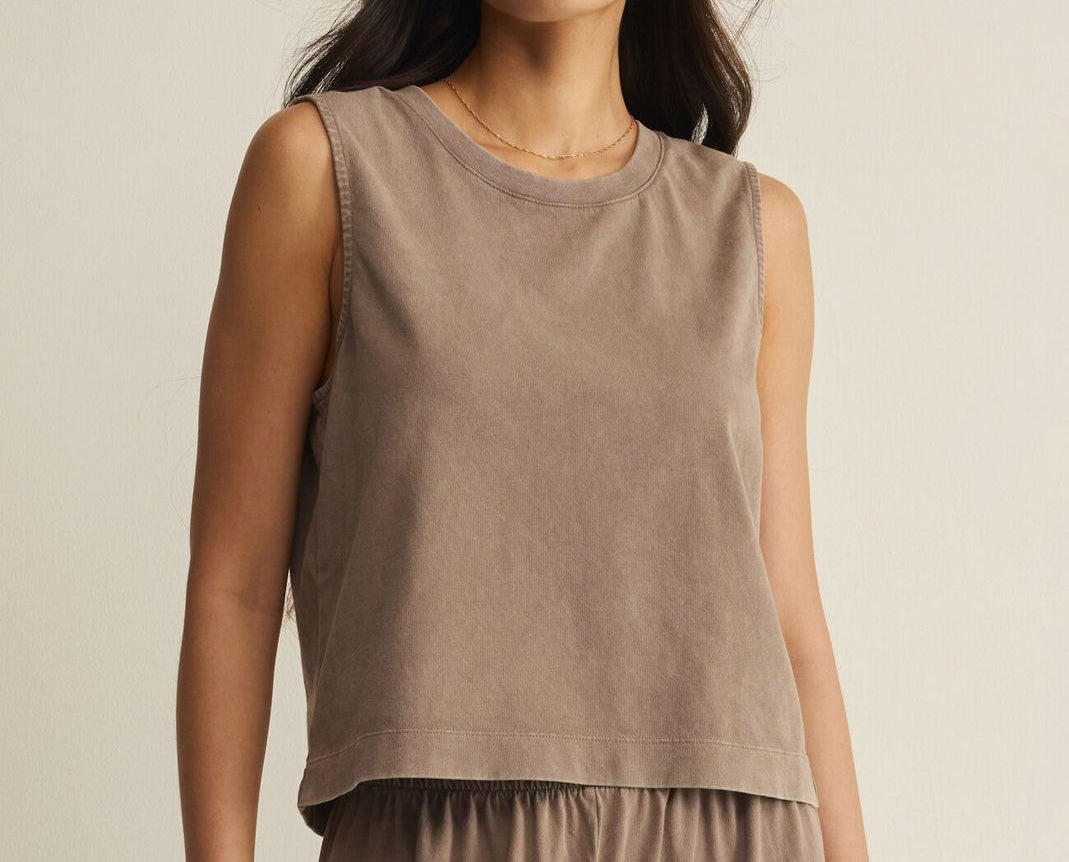 Woman wearing a brown sleeveless top and pants against a beige background