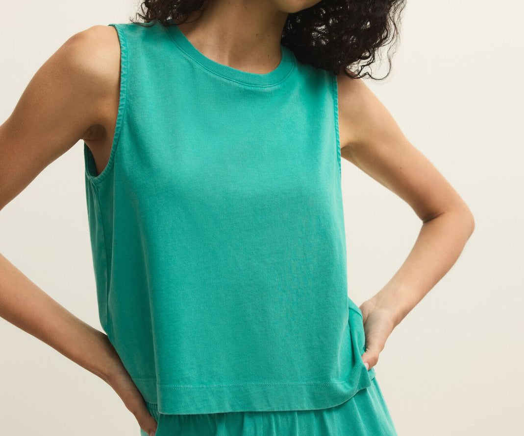 Woman wearing a green sleeveless top and pants against a beige background