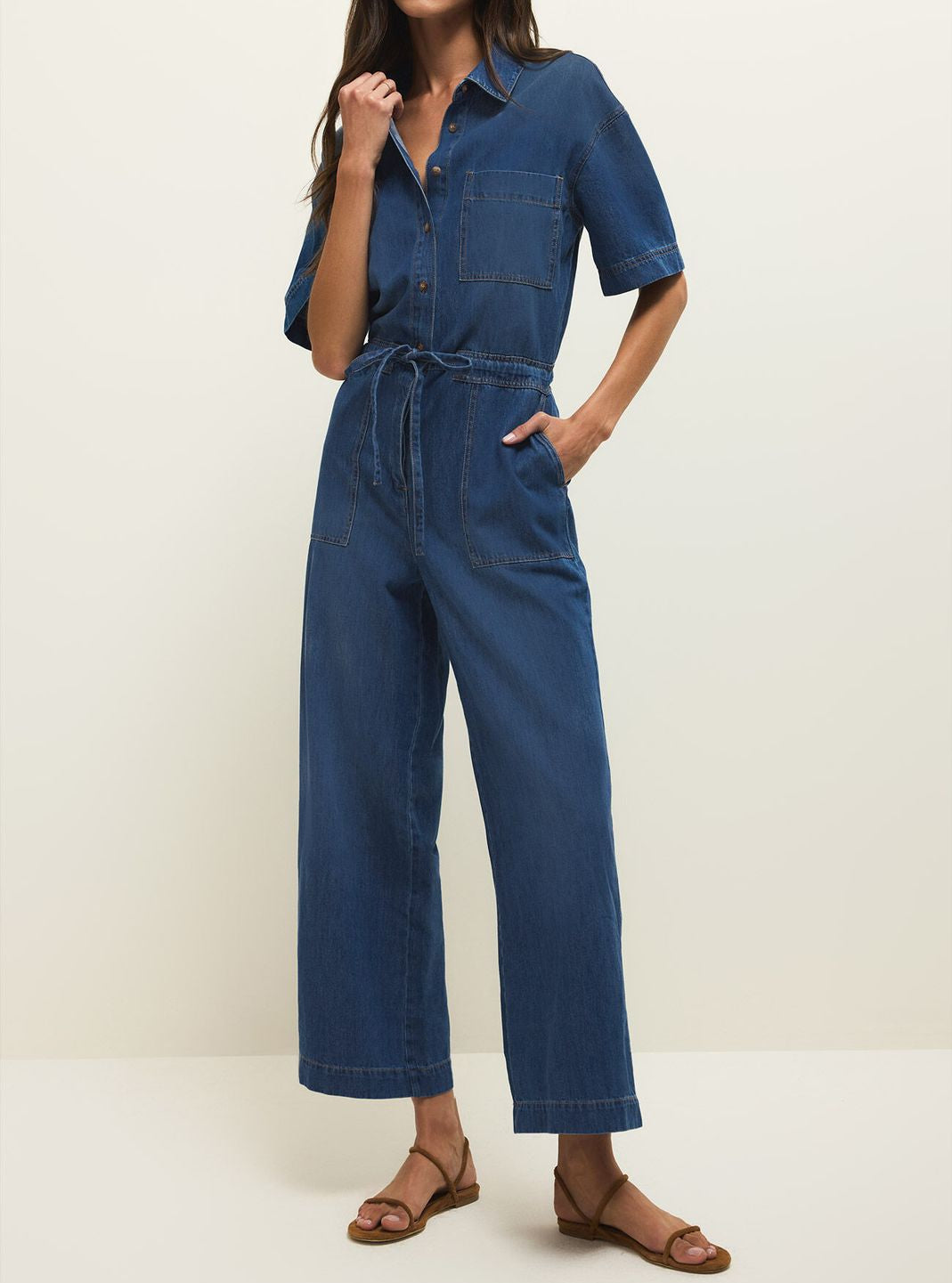Woman wearing a blue denim jumpsuit on a white background
