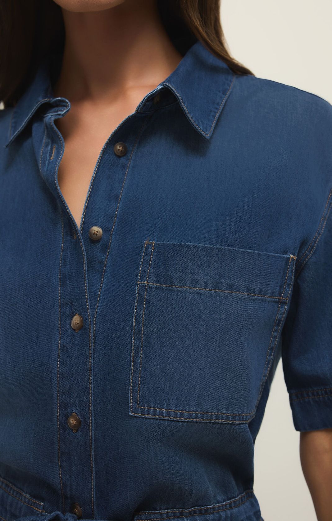 Close-up of a blue denim shirt with a pocket on a neutral background