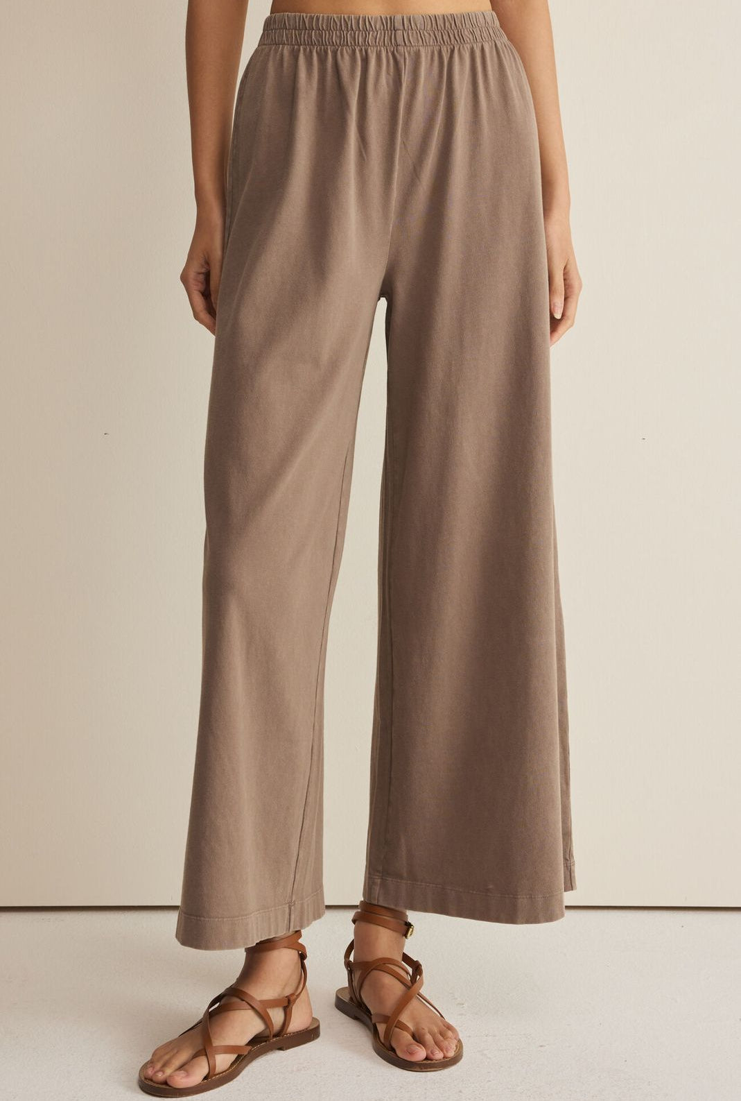 Person wearing beige wide-leg pants on a plain background