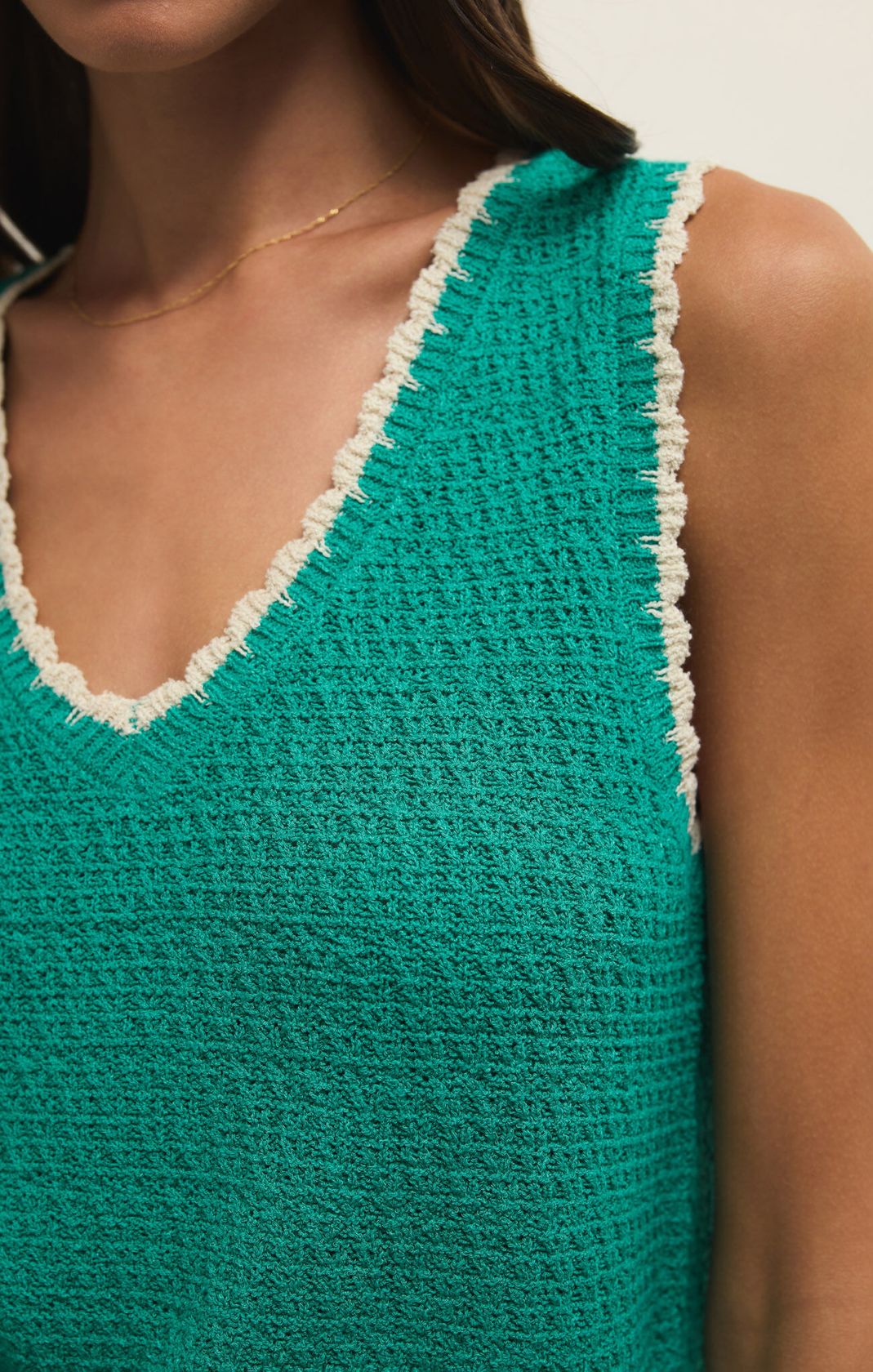 Green crochet top with white trim worn by a person