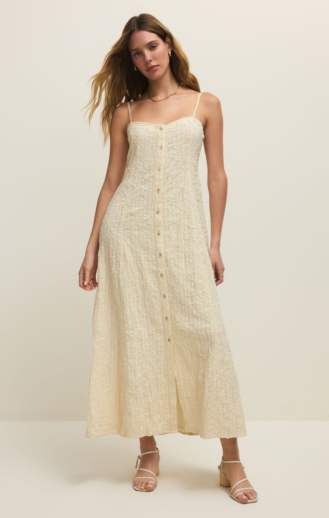 Woman wearing a beige button-up dress against a white background