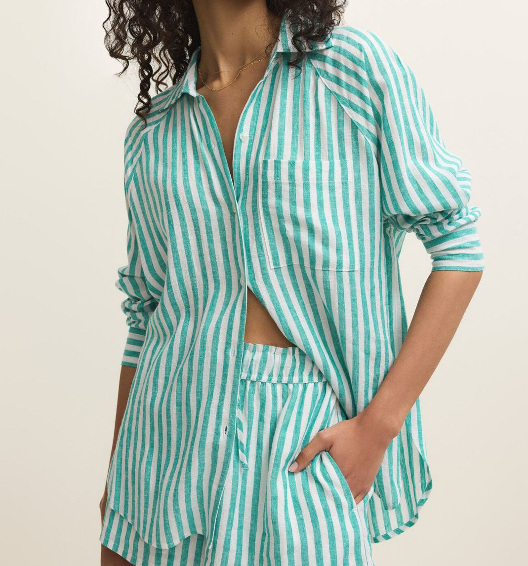Woman wearing a green and white striped shirt and shorts set on a beige background