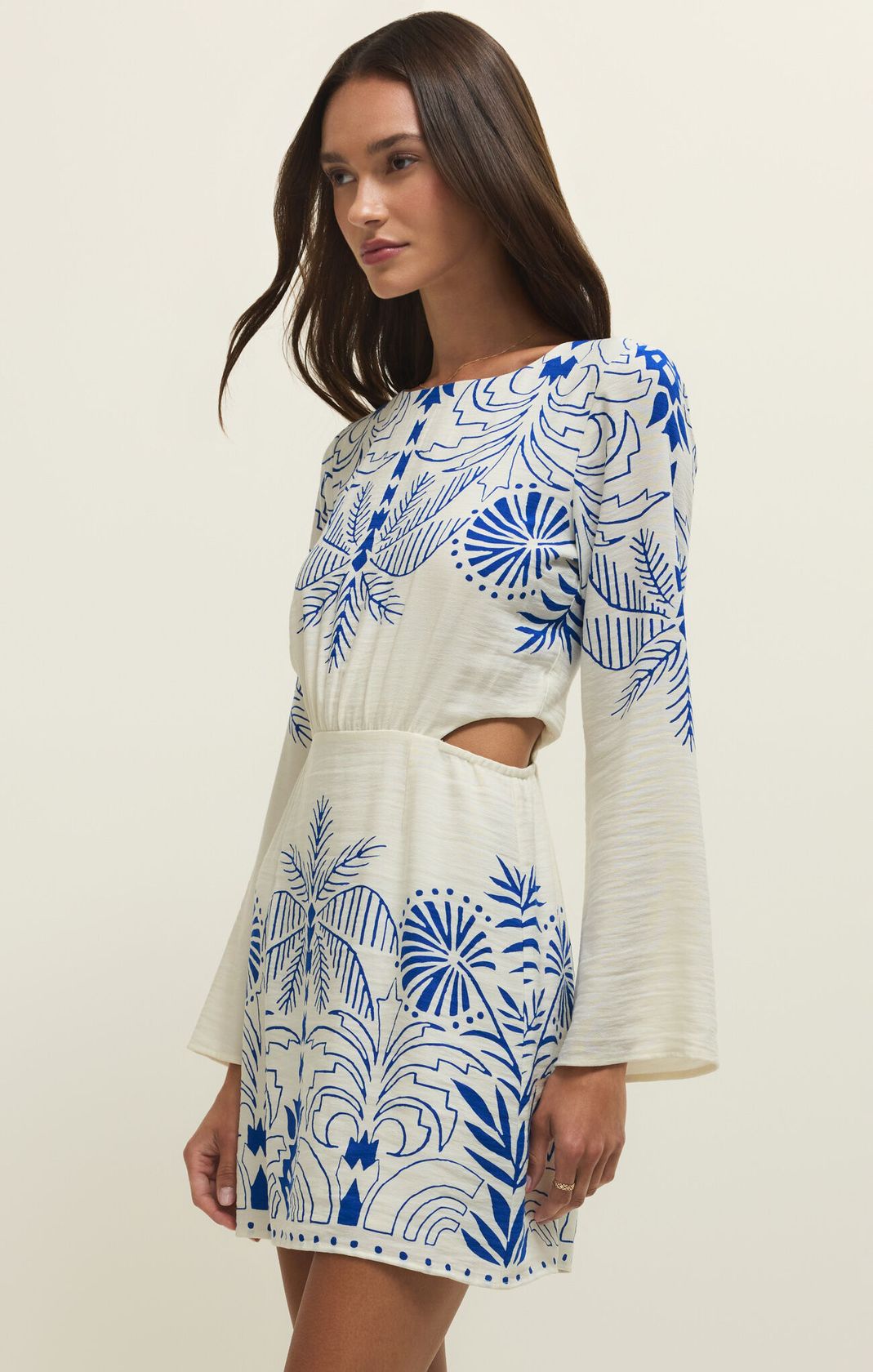 Woman wearing a white dress with blue floral patterns on a plain background