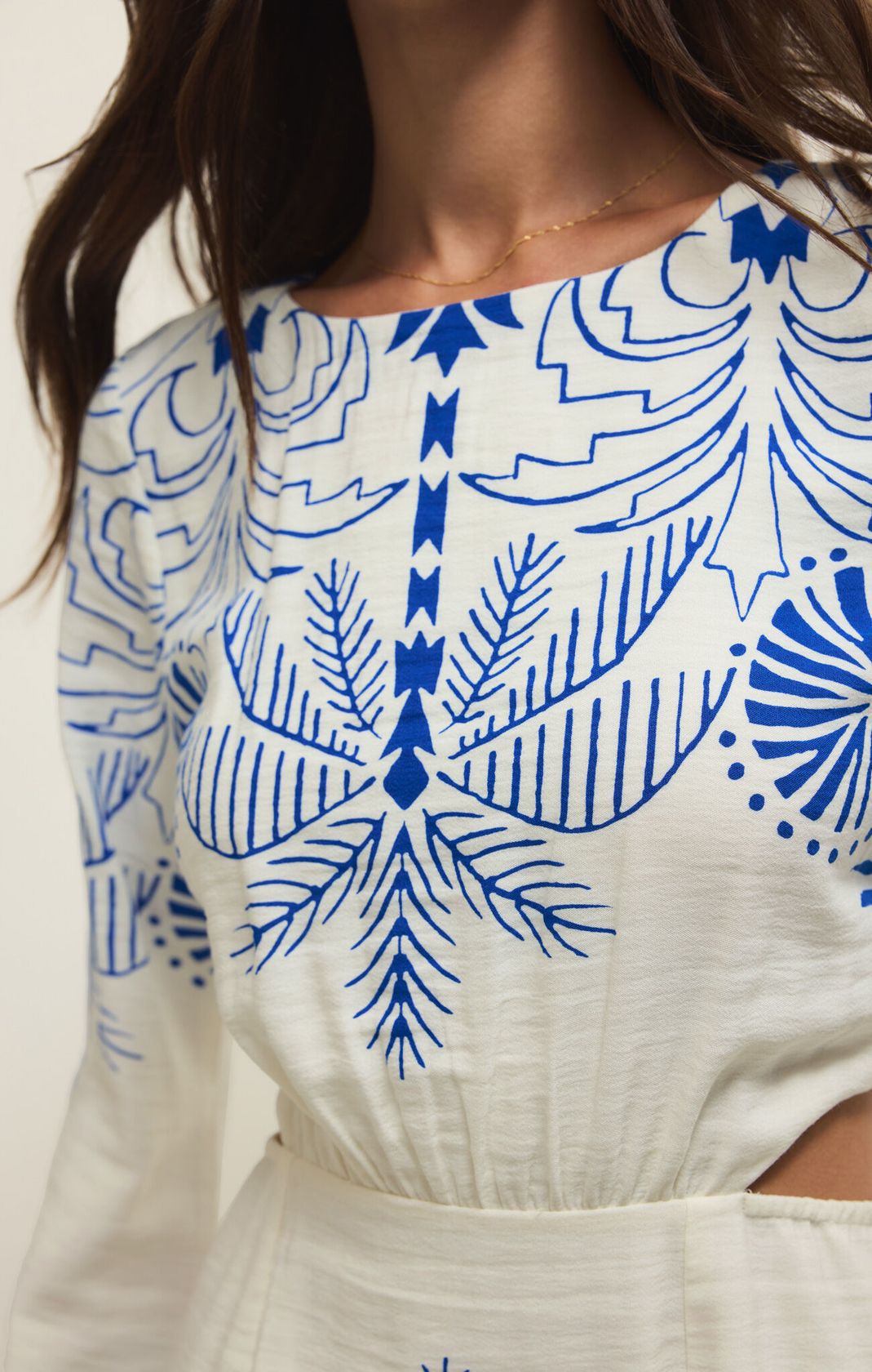 White dress with blue geometric pattern worn by a person