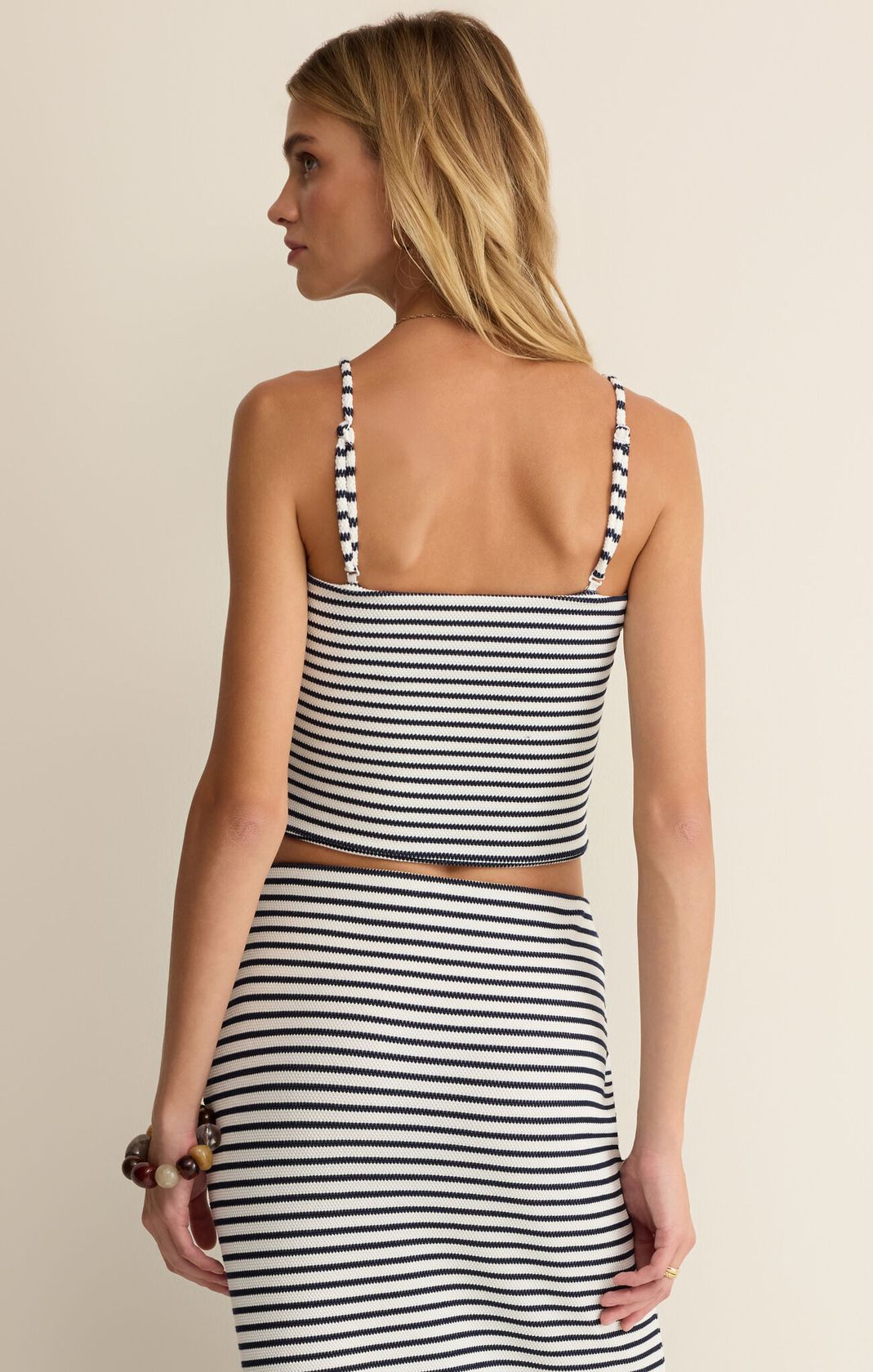 Woman wearing a black and white striped dress against a beige background