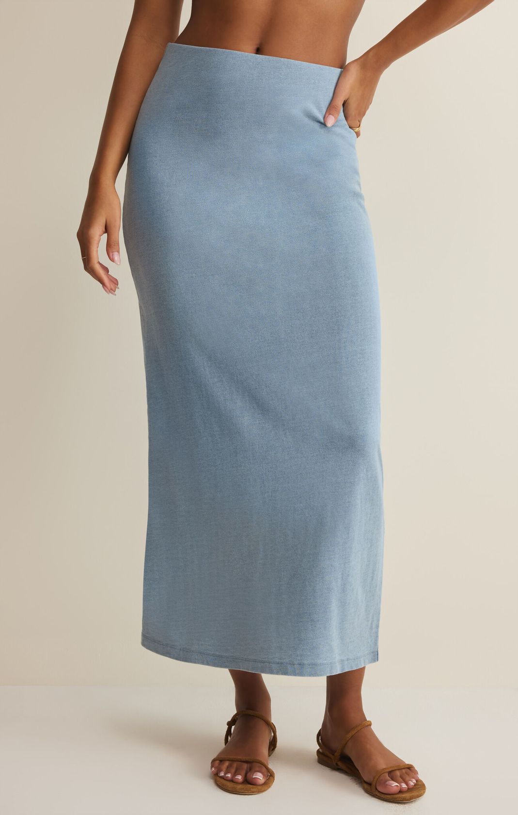 Person wearing a light blue skirt on a beige background