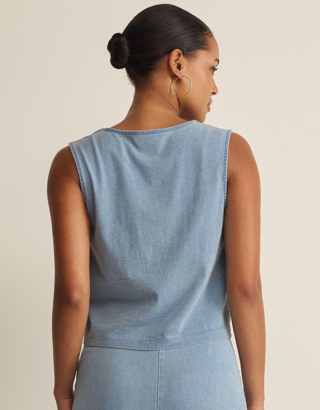Woman wearing a light blue sleeveless dress against a beige background