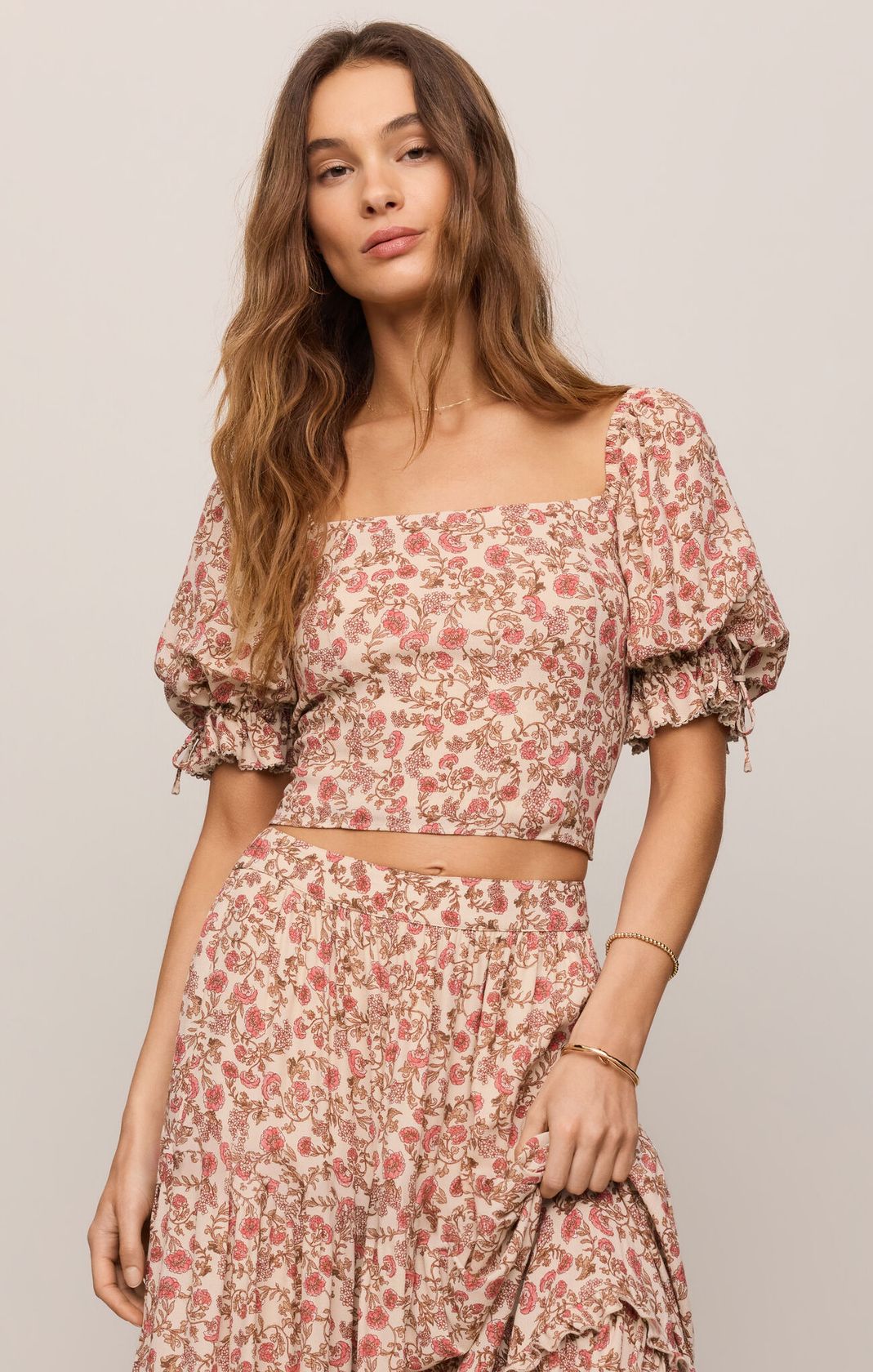 Woman wearing a floral two-piece outfit against a plain background