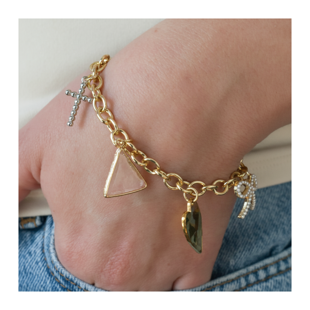 A gold-colored charm bracelet with various charms on it, worn on a person's wrist.
