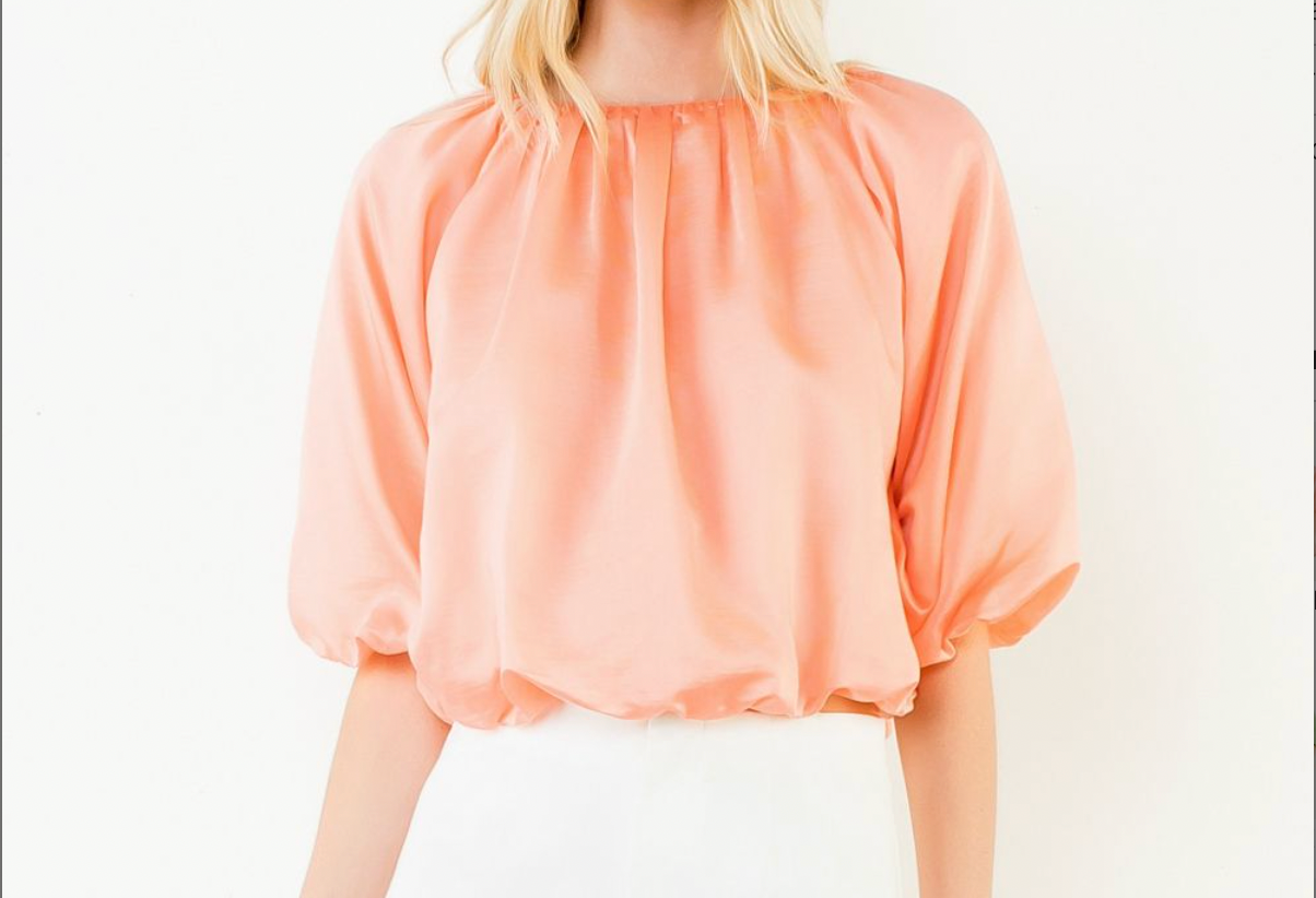 Person wearing a peach-colored blouse against a white background