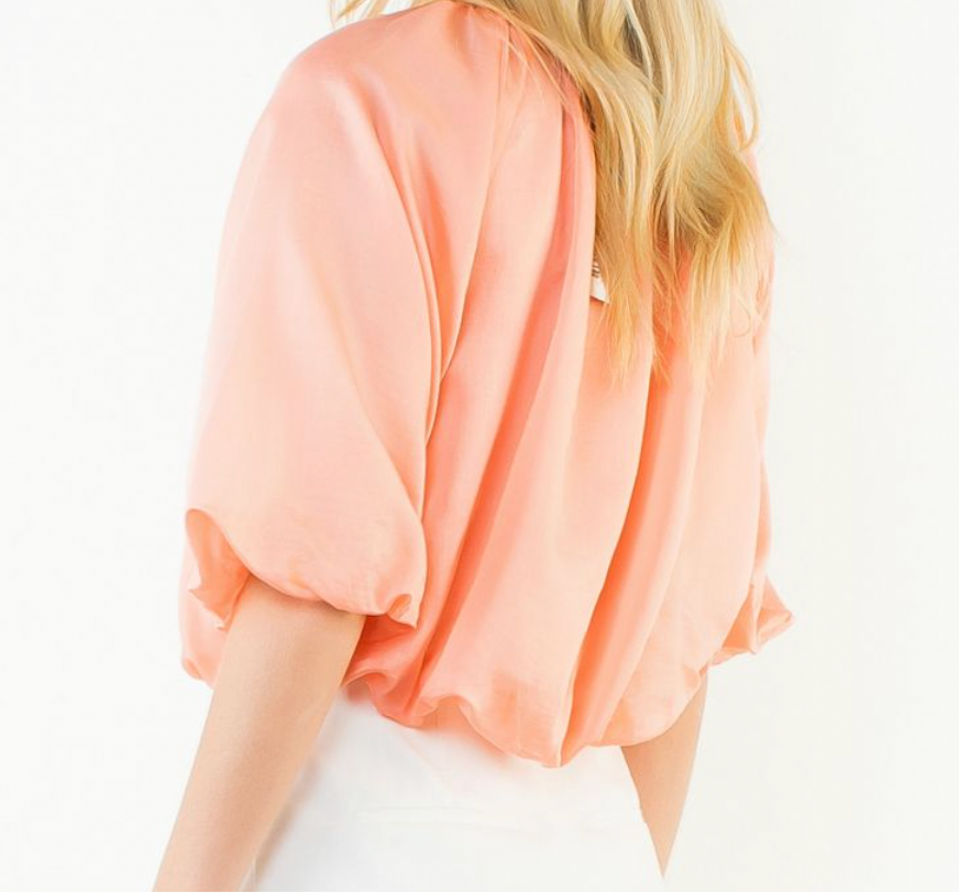 Person wearing a peach-colored top on a white background
