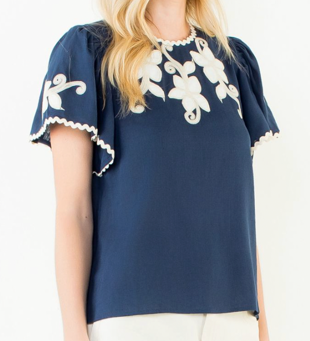 Navy blue top with white floral embroidery on a plain background
