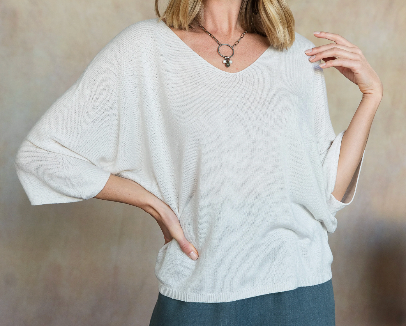 Person wearing a white sweater against a neutral background