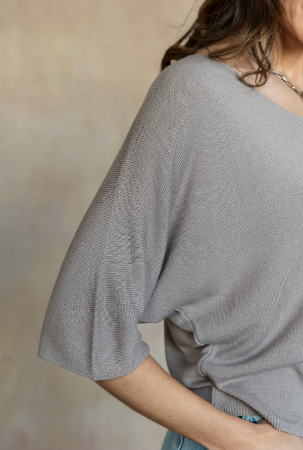 Person wearing a gray sweater against a neutral background